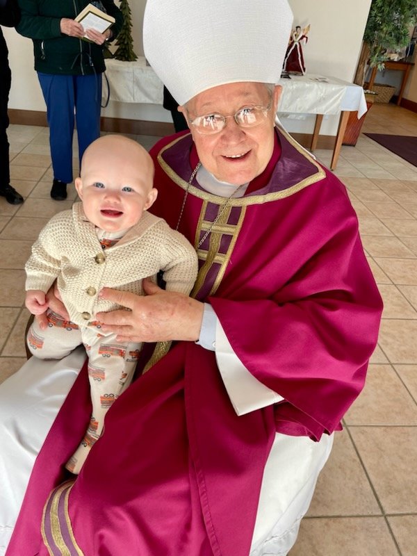 Bishop Emeritus John R. Gaydos greets who was probably the youngest congregant at the See City Deanery’s Memorial Mass for Pope Emeritus Benedict XVI on Jan. 6 in St. Andrew Church in Holts Summit.